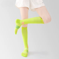 Bas de contention femme vert fluorescent sur une femme sur fond gris